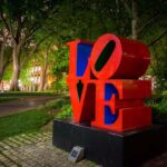 A shot of the Penn Love statue on college , with the bright red letters L O V E stacked on each other.